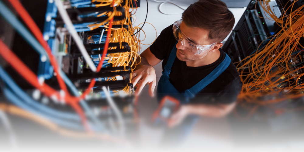 A man testing network cables in a network rack.